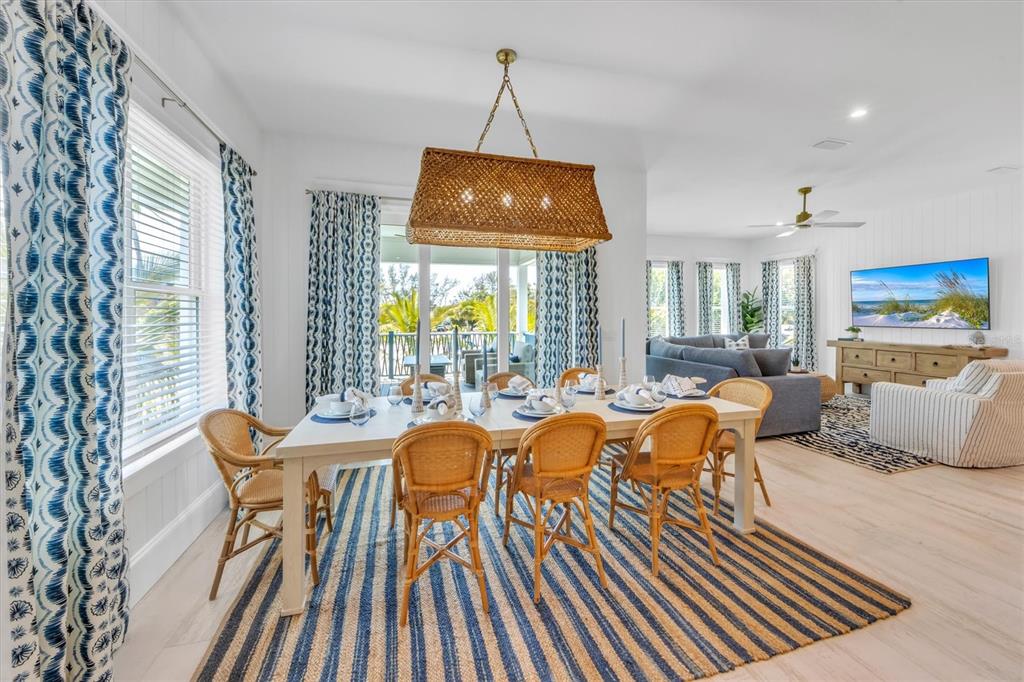 A dining area with a wicker chandelier, striped rug, and wicker chairs near a living room — 518 SPRING AVENUE, ANNA MARIA, FL