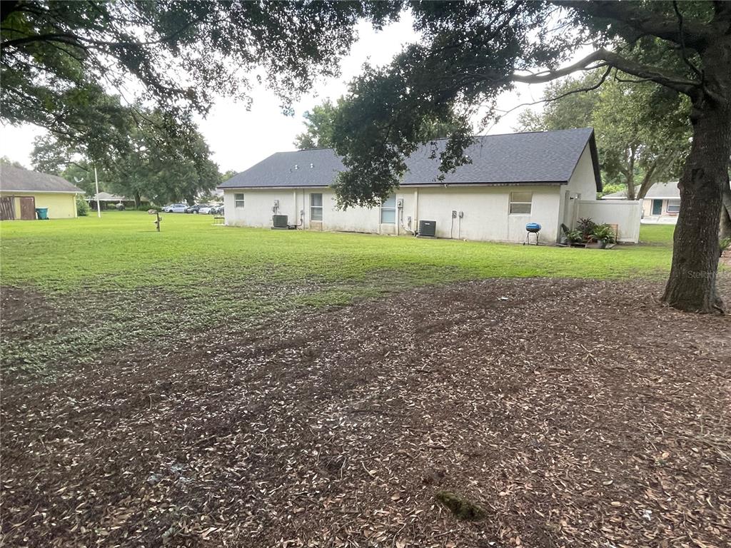 A view of a house exterior with a large grassy yard and mature trees — 1783 108TH LANE UNIT A & B, OCALA, FL