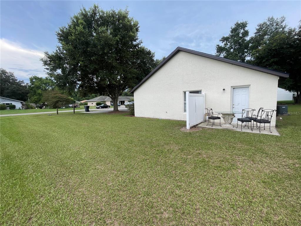 A side view of a house with a small patio, outdoor furniture, and a large tree — 1783 108TH LANE UNIT A & B, OCALA, FL