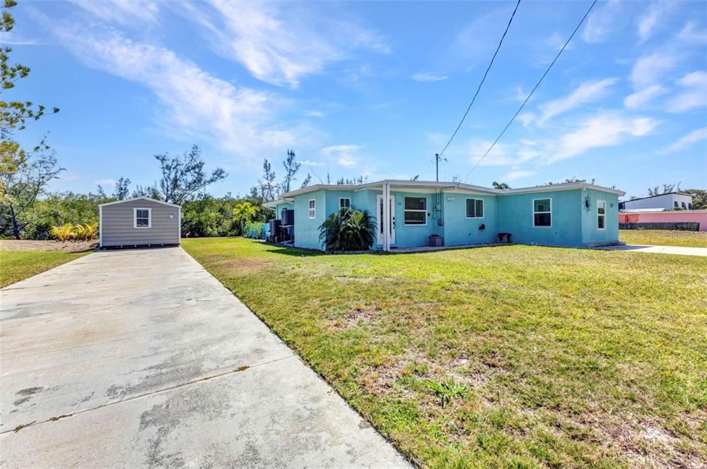 A light blue single-story house with a detached shed and a concrete driveway — 312 DARST AVENUE, PUNTA GORDA, FL