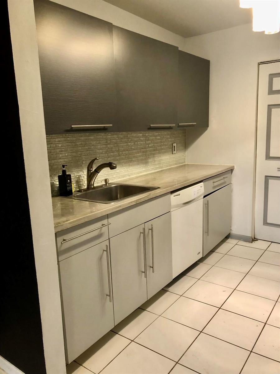 A kitchen features gray upper cabinets, light gray lower cabinets, a stainless sink, and tile flooring — 500 NE 2nd Street # 204, Dania Beach FL 33004, DANIA BEACH, FL