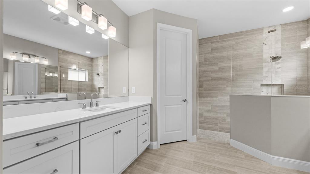 A bathroom features a white vanity with a quartz countertop, a walk-in shower, and tile flooring — 3099 HERITAGE PINES DRIVE, FORT MYERS, FL