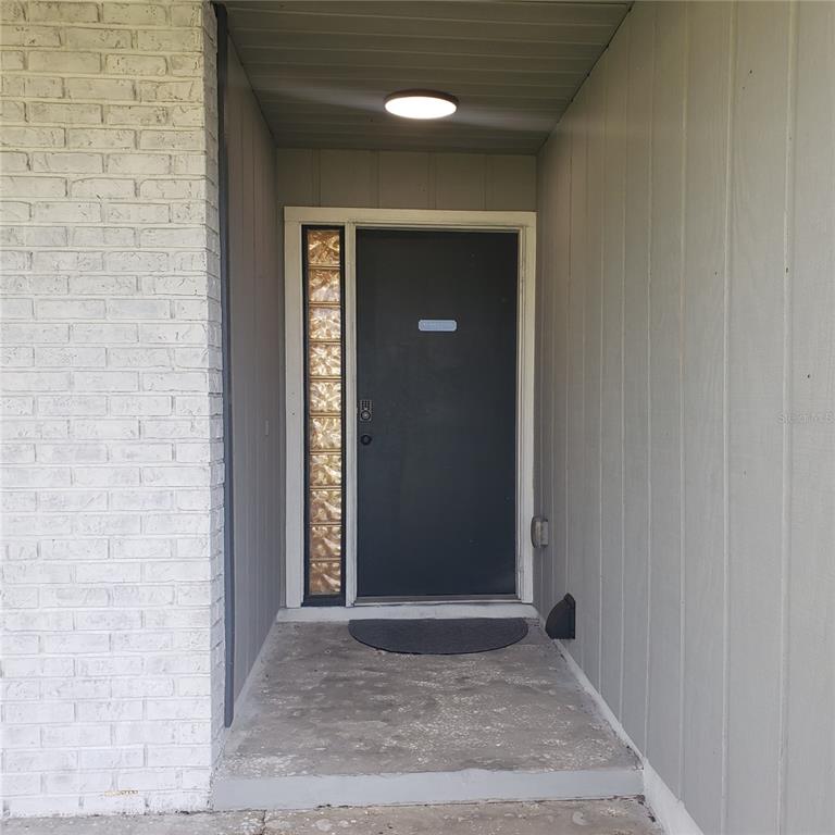 A front entryway features a dark door with a glass block sidelight and white brick — 404 KING LOUIS COURT, SEFFNER, FL