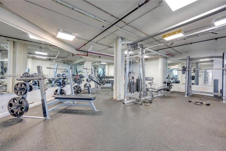 A gym room features weightlifting equipment, mirrors on the walls, and a rubberized floor — 999 Brickell Bay Dr # 2007, Miami FL 33131, MIAMI, FL