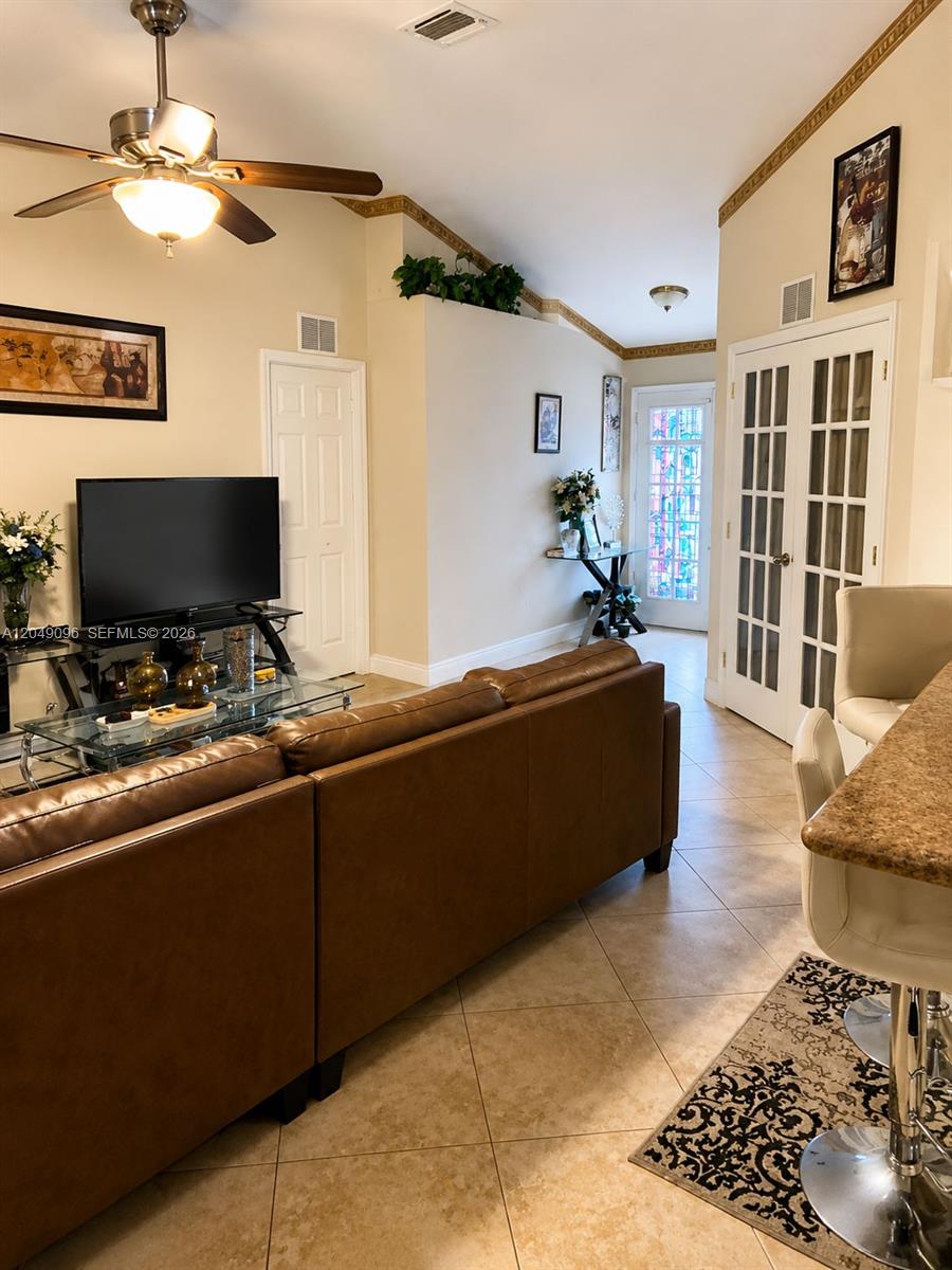 A living room features a brown leather sofa, a television, and tile flooring — 2903 19TH ST SW, Lehigh Acres FL 33976, LEHIGH ACRES, FL
