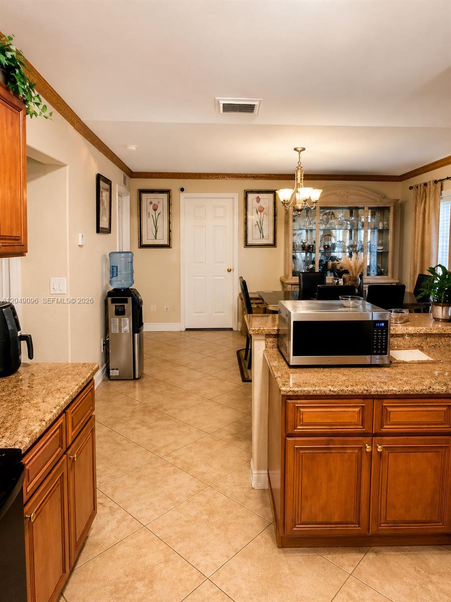 A kitchen with granite countertops and wood cabinets opens into a dining area — 2903 19TH ST SW, Lehigh Acres FL 33976, LEHIGH ACRES, FL