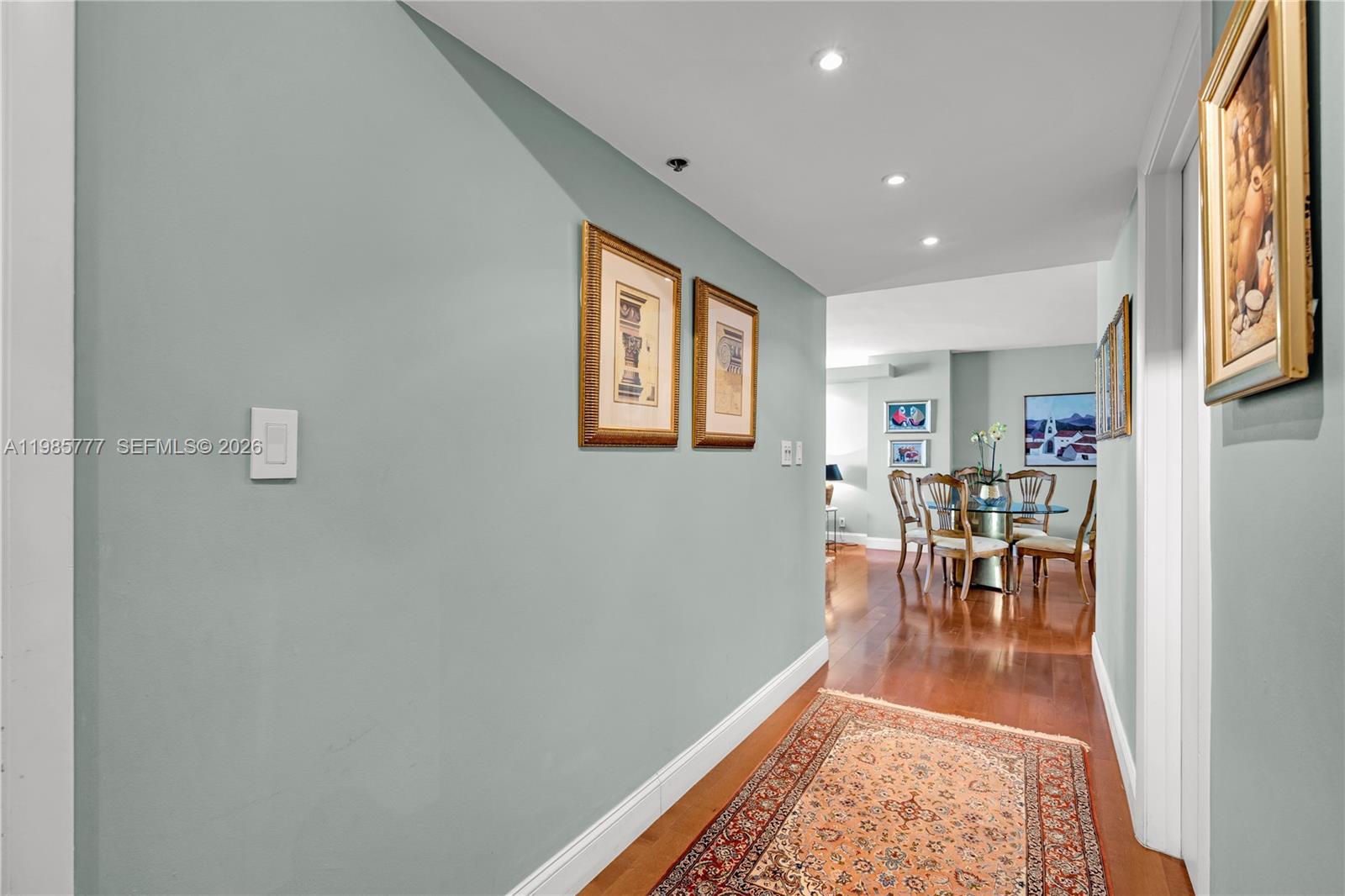 A hallway with hardwood floors and a rug leads to a dining area — 2025 Brickell Ave # 1703, Miami FL 33129, MIAMI, FL