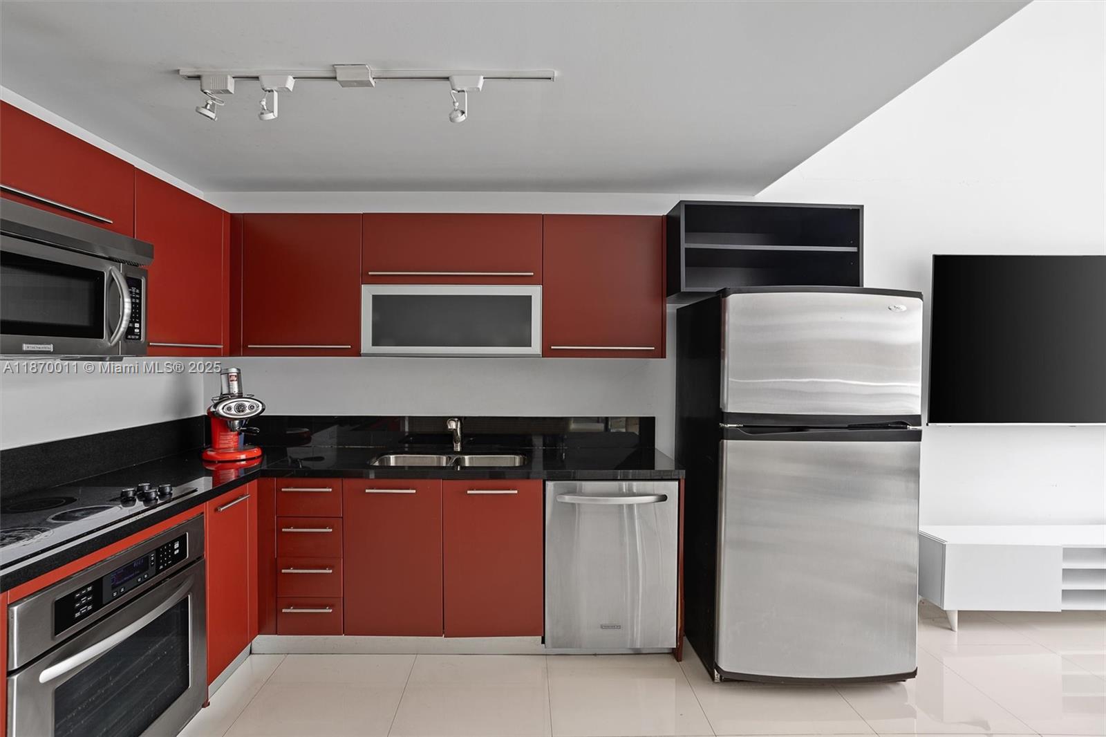 A modern kitchen features red cabinets, black countertops, stainless steel appliances, and track lighting — 253 NE 2 ST # 626, Miami FL 33132, MIAMI, FL