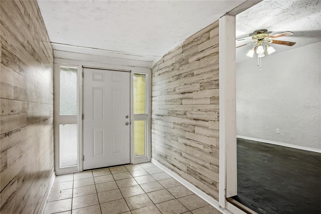 An entryway with tiled floors, wood-look wall paneling, and a white front door with sidelights — 1334 NE 1ST AVENUE, GAINESVILLE, FL