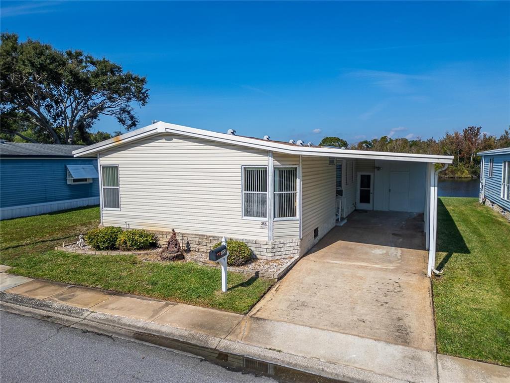 A single-story manufactured home with light siding, a concrete driveway, and a carport — 1001 STARKEY ROAD, LOT#355, LARGO, FL