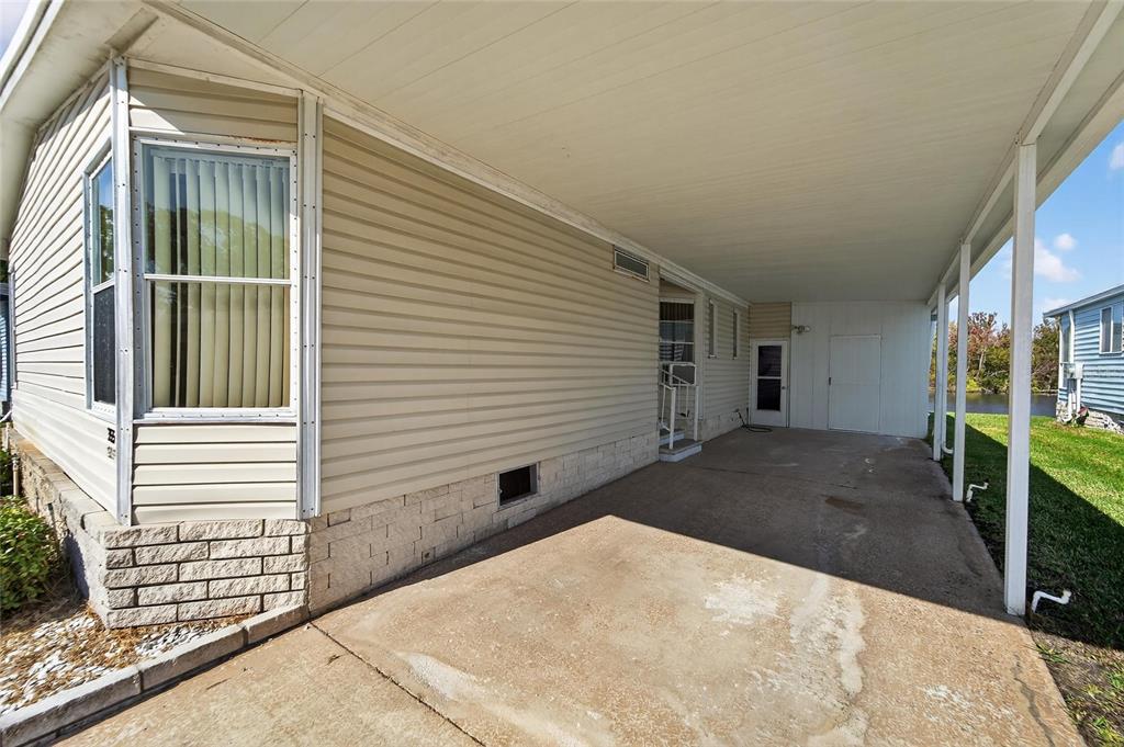 A beige mobile home features a concrete carport and a stone-patterned foundation — 1001 STARKEY ROAD, LOT#355, LARGO, FL