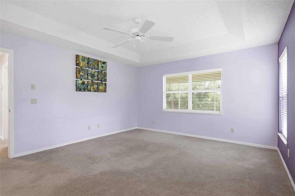 A bedroom with light purple walls, carpeted flooring, a ceiling fan, and a window — 1204 N MEDITERRANEAN WAY, INVERNESS, FL
