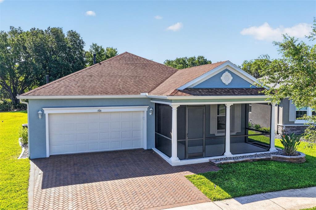 A single-story house features a blue exterior, a two-car garage, and a screened-in front porch — 769 ALCOVE DR, GROVELAND, FL