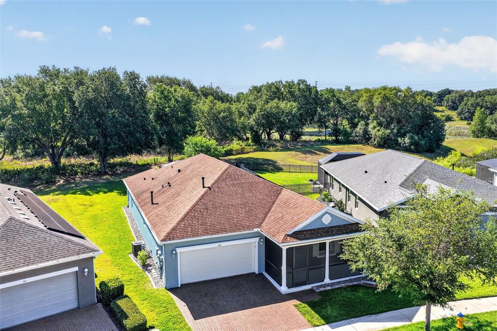 An aerial view shows a blue suburban house with a brown roof and screened porch — 769 ALCOVE DR, GROVELAND, FL
