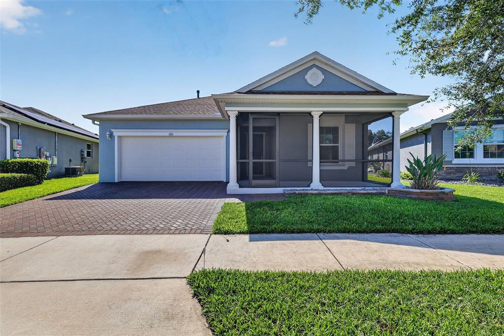 A light blue single-story house features a two-car garage and a screened-in front porch — 769 ALCOVE DR, GROVELAND, FL