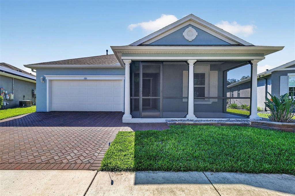 A single-story house with a brick driveway, a two-car garage, and a screened front porch — 769 ALCOVE DR, GROVELAND, FL