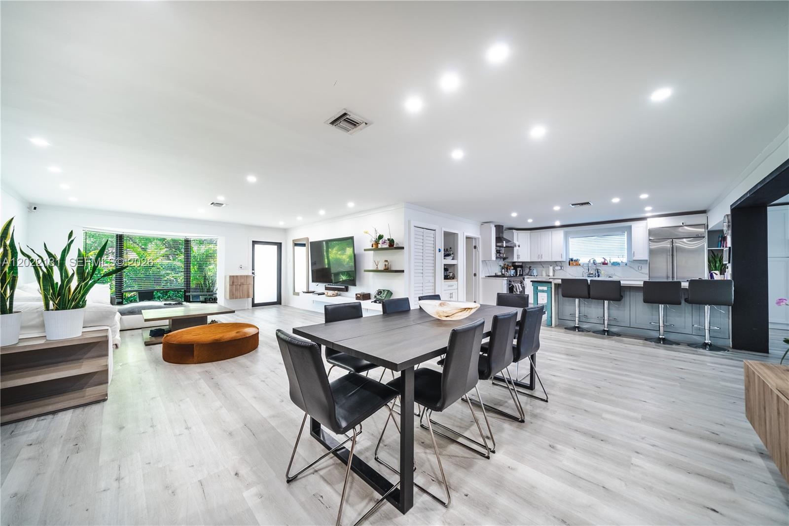 An open-concept living and dining area features light wood flooring, a modern kitchen, and recessed lighting — 1301 Funston St, Hollywood FL 33019, HOLLYWOOD, FL