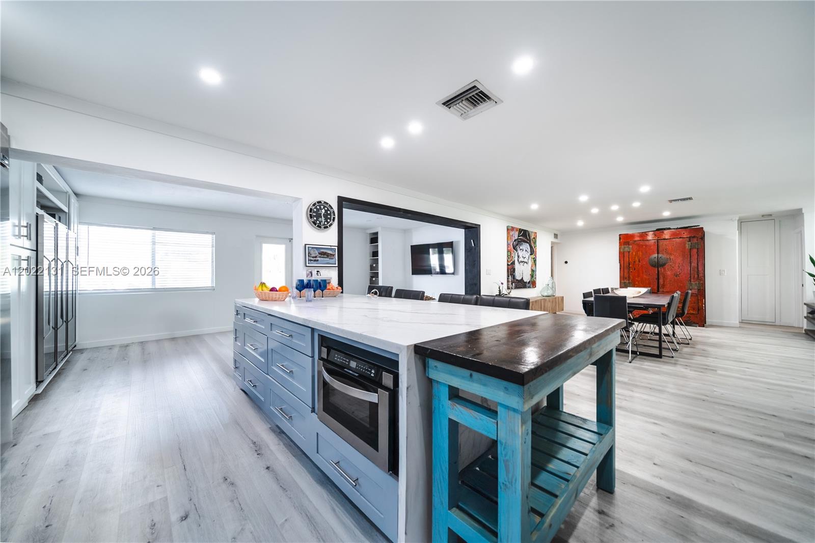 A kitchen features a large island with a blue base, marble countertop, and attached wooden table — 1301 Funston St, Hollywood FL 33019, HOLLYWOOD, FL