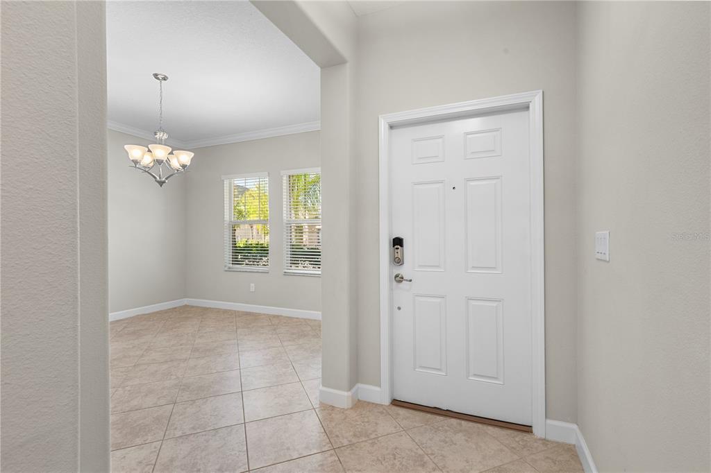 An entryway with tile flooring leads to a dining room featuring a chandelier and windows — 3147 CALVANO DRIVE, LAND O LAKES, FL