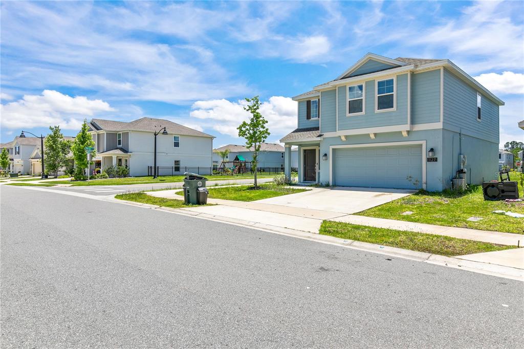A two-story light blue house with a two-car garage sits on a suburban street — 1127 CABOT CLIFFS DRIVE, DAYTONA BEACH, FL