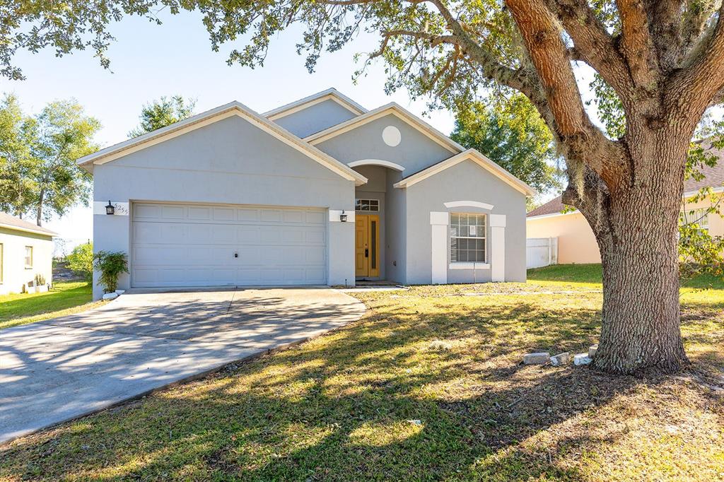 A light blue single-story house with a two-car garage and a large front yard tree — 5255 SHALE RIDGE TRAIL, ORLANDO, FL