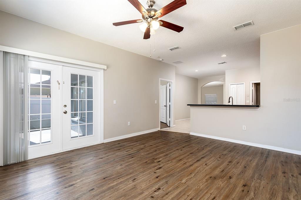 An empty living room with wood-look flooring, a ceiling fan, and a glass patio door — 5255 SHALE RIDGE TRAIL, ORLANDO, FL