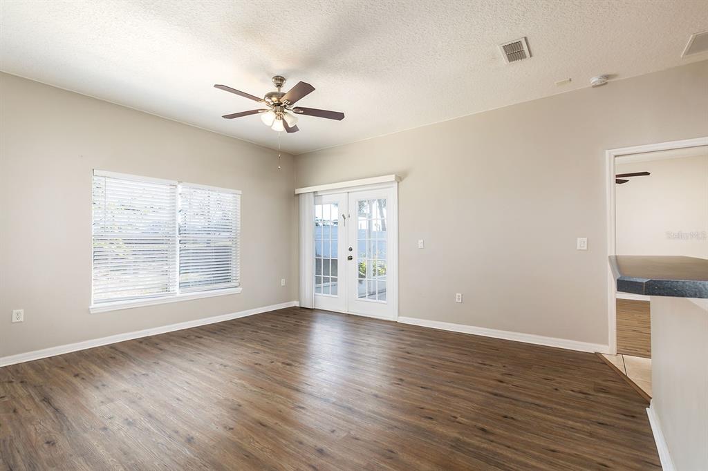 An empty living room with wood-look flooring, a ceiling fan, and glass patio doors — 5255 SHALE RIDGE TRAIL, ORLANDO, FL