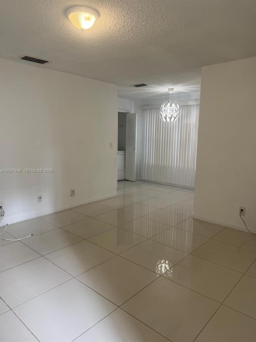 A bright, empty room features white walls, glossy tile flooring, and two overhead light fixtures — MARGATE, FL