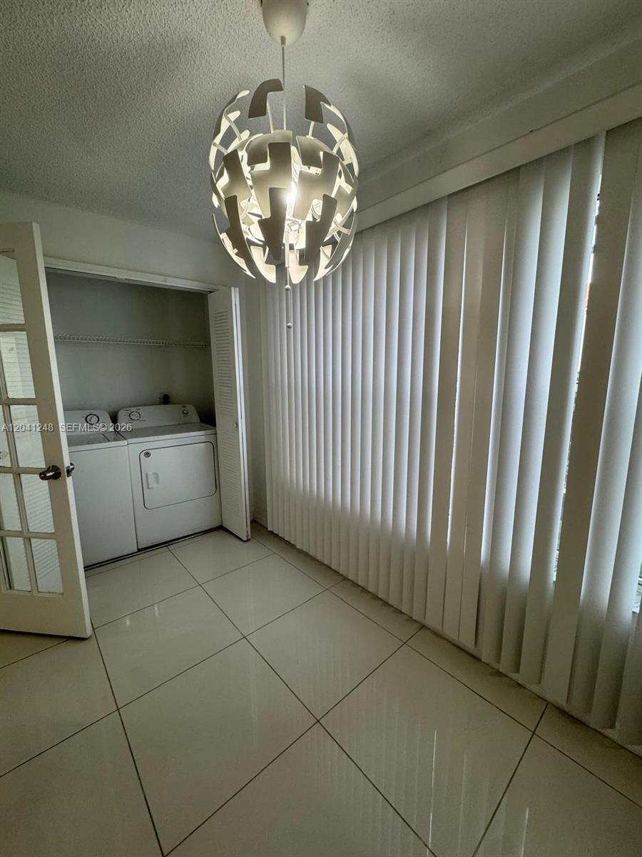 A laundry room features white tile flooring, a modern pendant light, and a closet area — MARGATE, FL