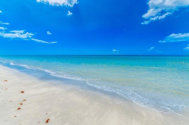 A sandy beach meets the turquoise ocean under a bright blue sky with scattered clouds — 1270 GULF BOULEVARD UNIT 304, CLEARWATER, FL