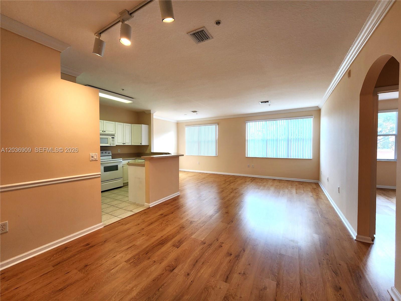An open-concept living area features wood-look flooring, beige walls, and an adjacent kitchen — 4602 SW 160th Ave # 524, Miramar FL 33027, MIRAMAR, FL