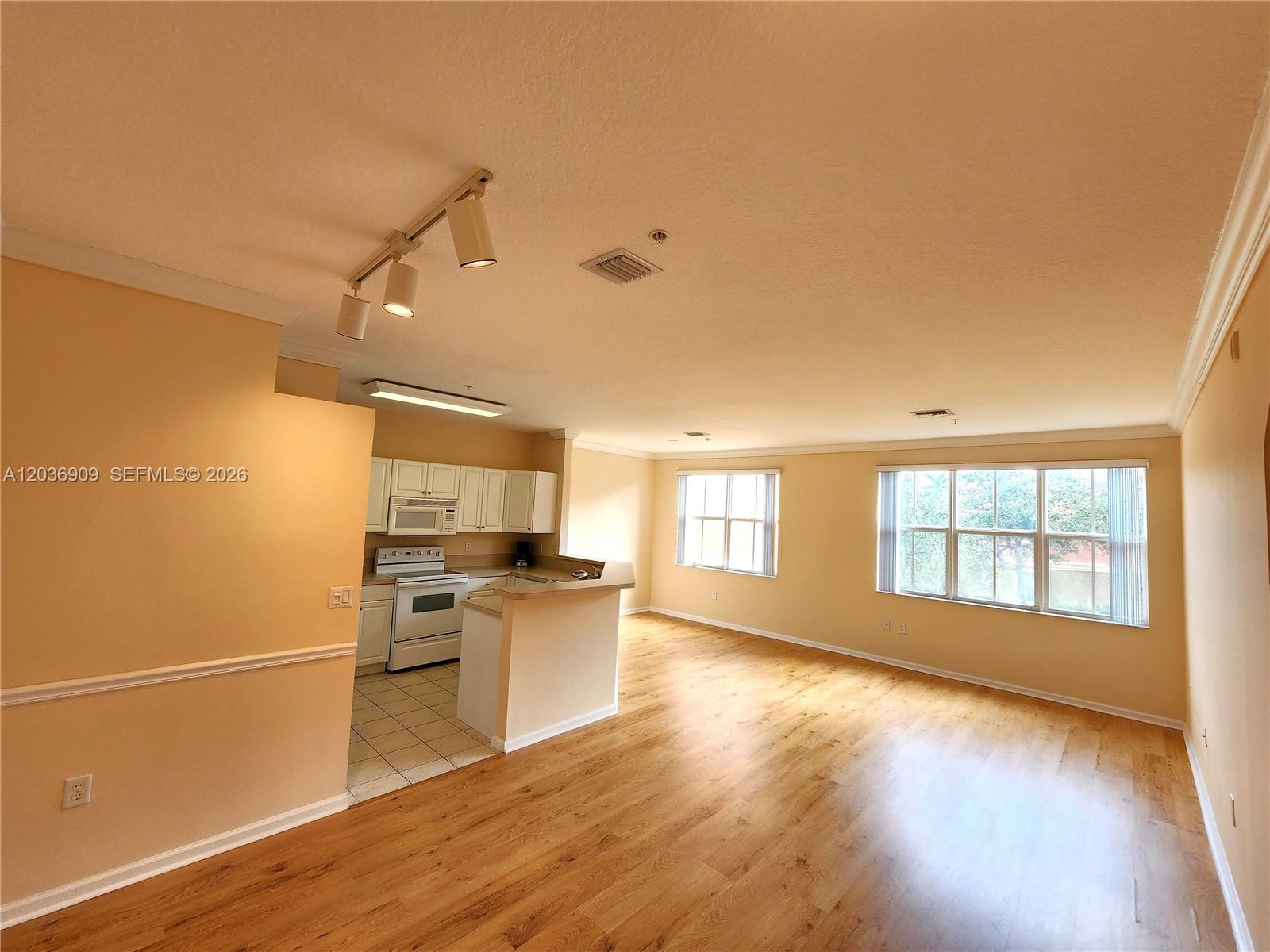 An open-concept living area features light wood flooring, beige walls, and an adjacent kitchen — 4602 SW 160th Ave # 524, Miramar FL 33027, MIRAMAR, FL