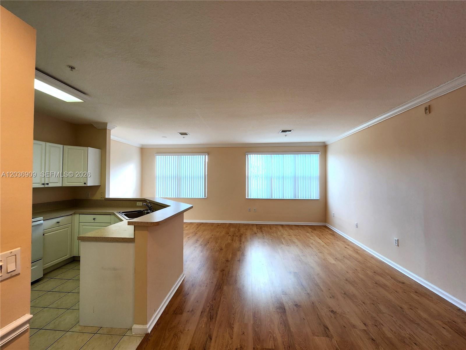 An open-concept living area features wood-look flooring and a kitchen with white cabinets — 4602 SW 160th Ave # 524, Miramar FL 33027, MIRAMAR, FL