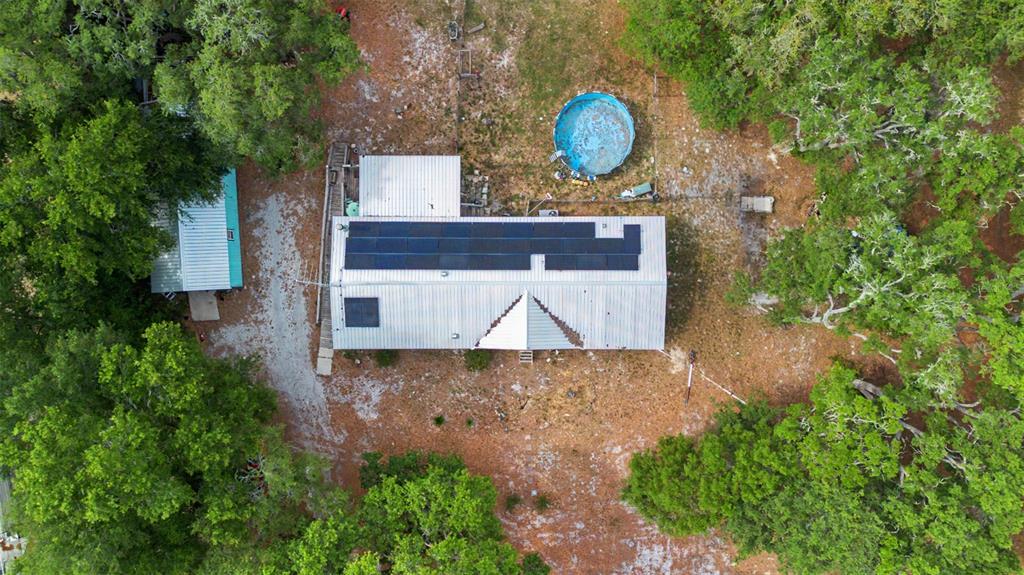 A long concrete driveway leads to a mobile home surrounded by large, mature oak trees — 8186 E WINDSONG STREET, FLORAL CITY, FL