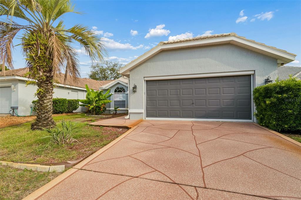A single-story house with a gray garage door and a decorative concrete driveway — 9376 FRENCH QUARTERS CIRCLE, WEEKI WACHEE, FL