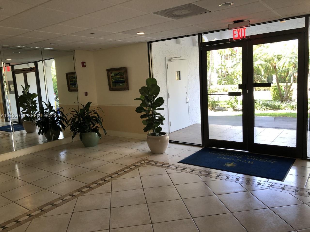 A tiled lobby entrance features glass doors, potted plants, and a mirrored wall — 150 Ocean Lane Dr # 4B, Key Biscayne FL 33149, KEY BISCAYNE, FL