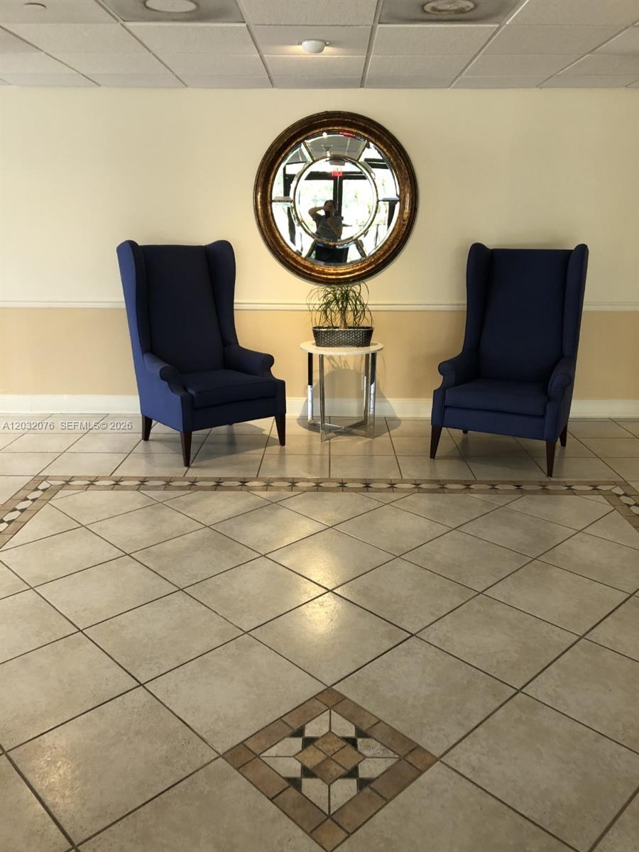 A lobby area features two blue wingback chairs, a small side table, and a round mirror — 150 Ocean Lane Dr # 4B, Key Biscayne FL 33149, KEY BISCAYNE, FL