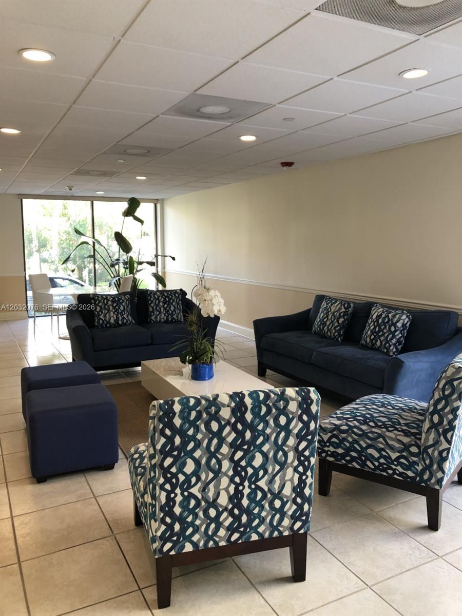 A furnished lobby features blue sofas, patterned armchairs, a white coffee table, and tile flooring — 150 Ocean Lane Dr # 4B, Key Biscayne FL 33149, KEY BISCAYNE, FL