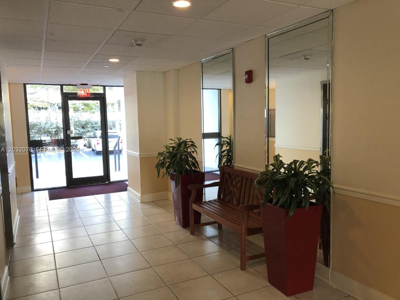 A tiled hallway features a wooden bench, two potted plants, and large wall mirrors — 150 Ocean Lane Dr # 4B, Key Biscayne FL 33149, KEY BISCAYNE, FL