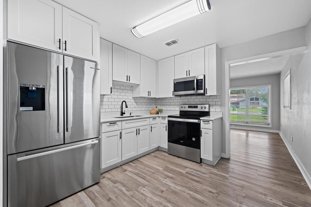 A kitchen with white cabinets, stainless steel appliances, and a subway tile backsplash — 305 E BOUGAINVILLEA AVENUE, TAMPA, FL