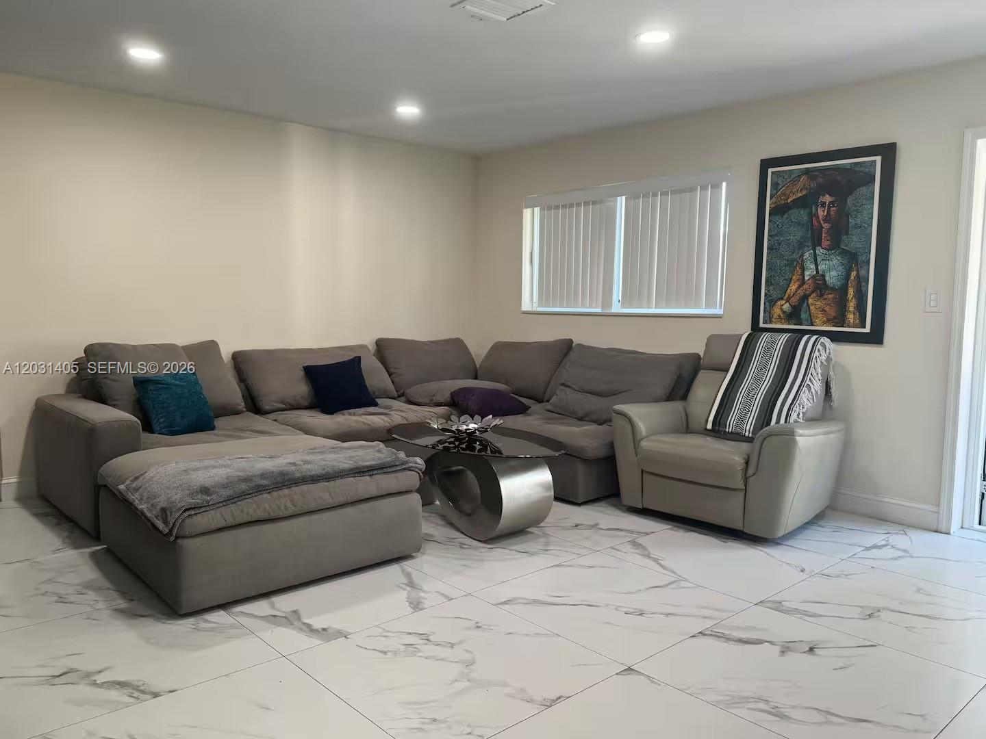 A living room features a large gray sectional sofa, a matching armchair, and marble-look tile flooring — 1716 Liberty St, Hollywood FL 33020, HOLLYWOOD, FL