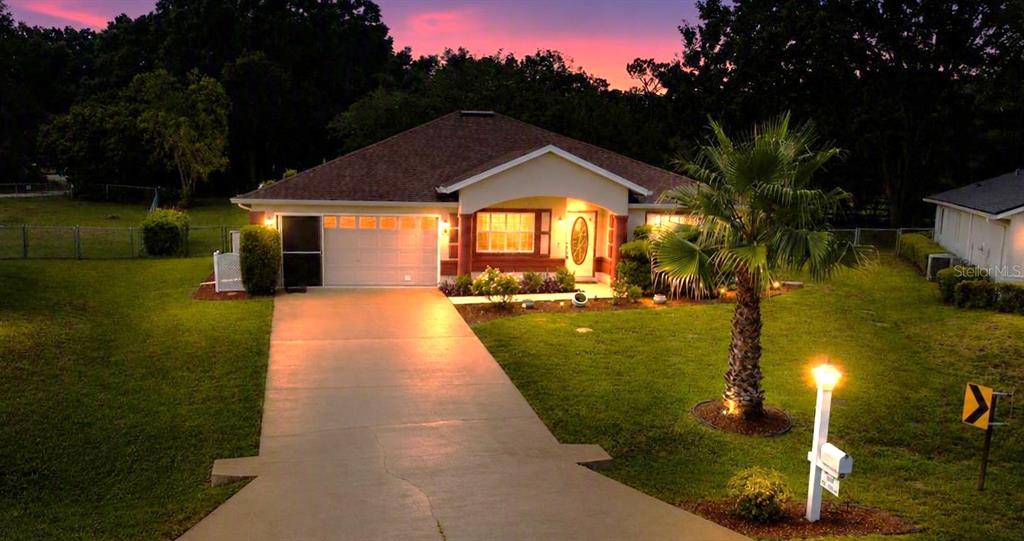 A single-story house with a driveway, garage, and palm tree at dusk — 6008 SW 103RD LOOP, OCALA, FL