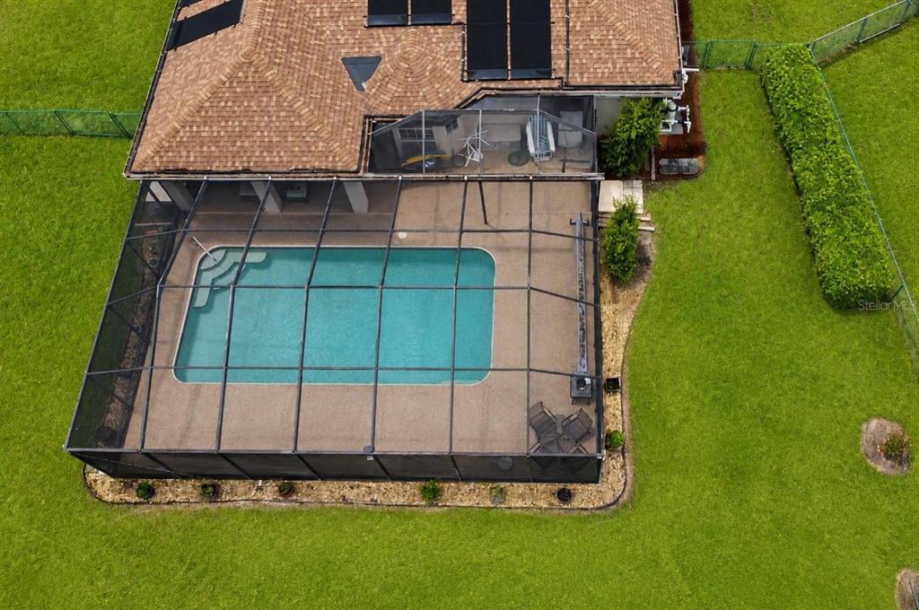 A swimming pool with a screen enclosure sits on a patio next to a house — 6008 SW 103RD LOOP, OCALA, FL