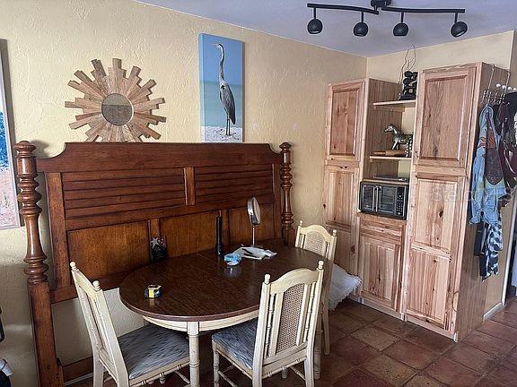 A dining area features a wooden table, chairs, a large headboard, and wooden cabinetry — 525 MANATEE COURT UNIT 8, VENICE, FL