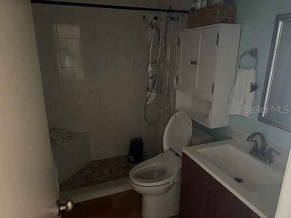 A bathroom features a tiled walk-in shower, a toilet, and a vanity with a sink — 525 MANATEE COURT UNIT 8, VENICE, FL