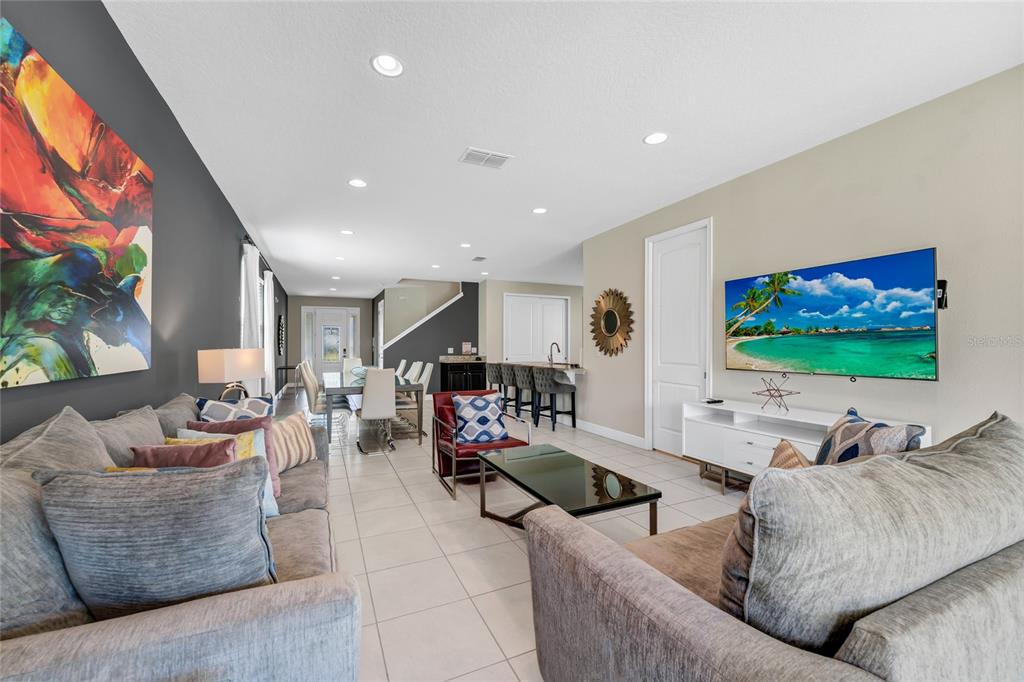 A living room features gray sofas, a glass coffee table, and a wall-mounted television — 7708 GRABEN STREET, KISSIMMEE, FL