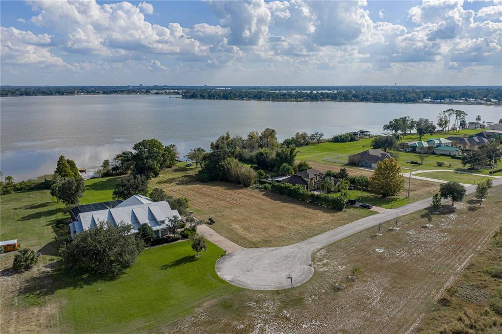 An aerial view shows a waterfront property with a large house, vacant lot, and cul-de-sac — 2080 KENNWOOD GROVE LANE, AUBURNDALE, FL