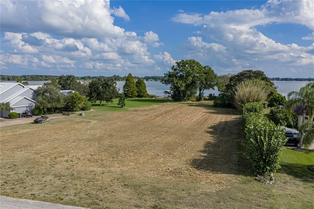 An elevated view of a vacant, grassy lot overlooking a lake under a cloudy sky — 2080 KENNWOOD GROVE LANE, AUBURNDALE, FL