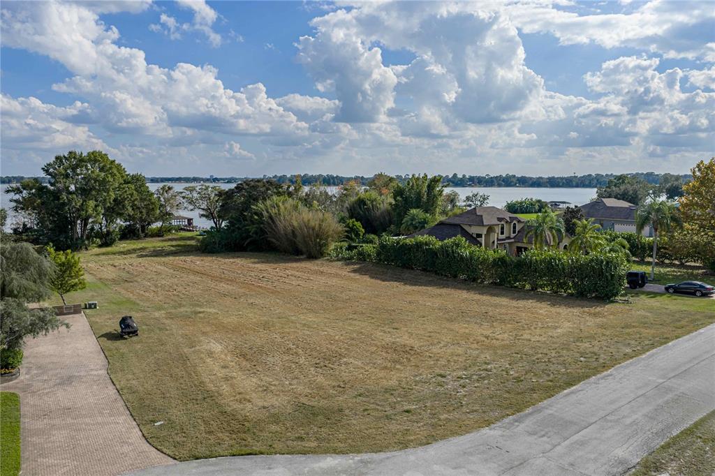 An aerial view shows a vacant, grassy lot situated next to a house and water — 2080 KENNWOOD GROVE LANE, AUBURNDALE, FL