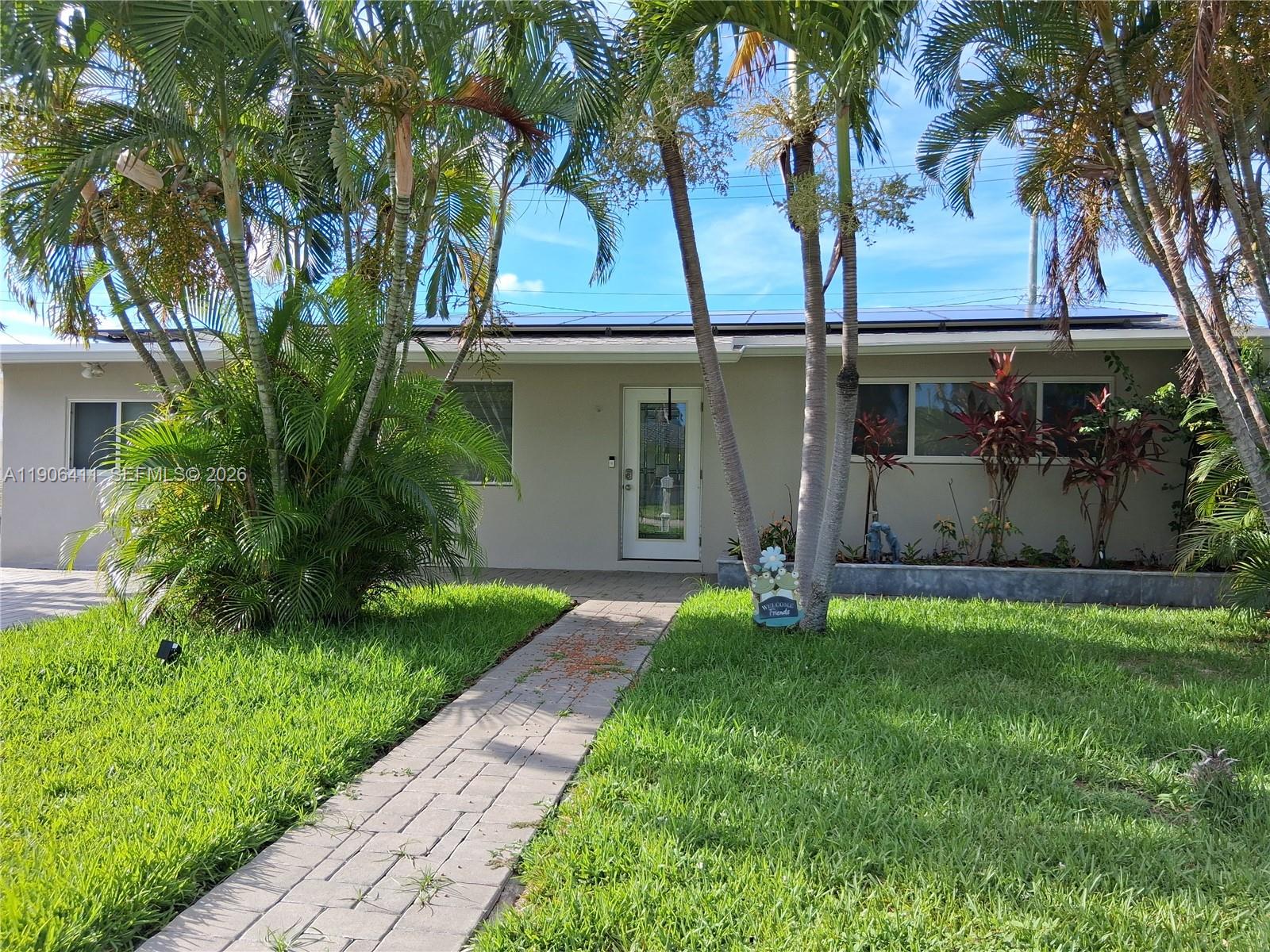 A single-story house with a paved walkway, palm trees, and solar panels on the roof — 717 SE 2nd St, Deerfield Beach FL 33441, DEERFIELD BEACH, FL
